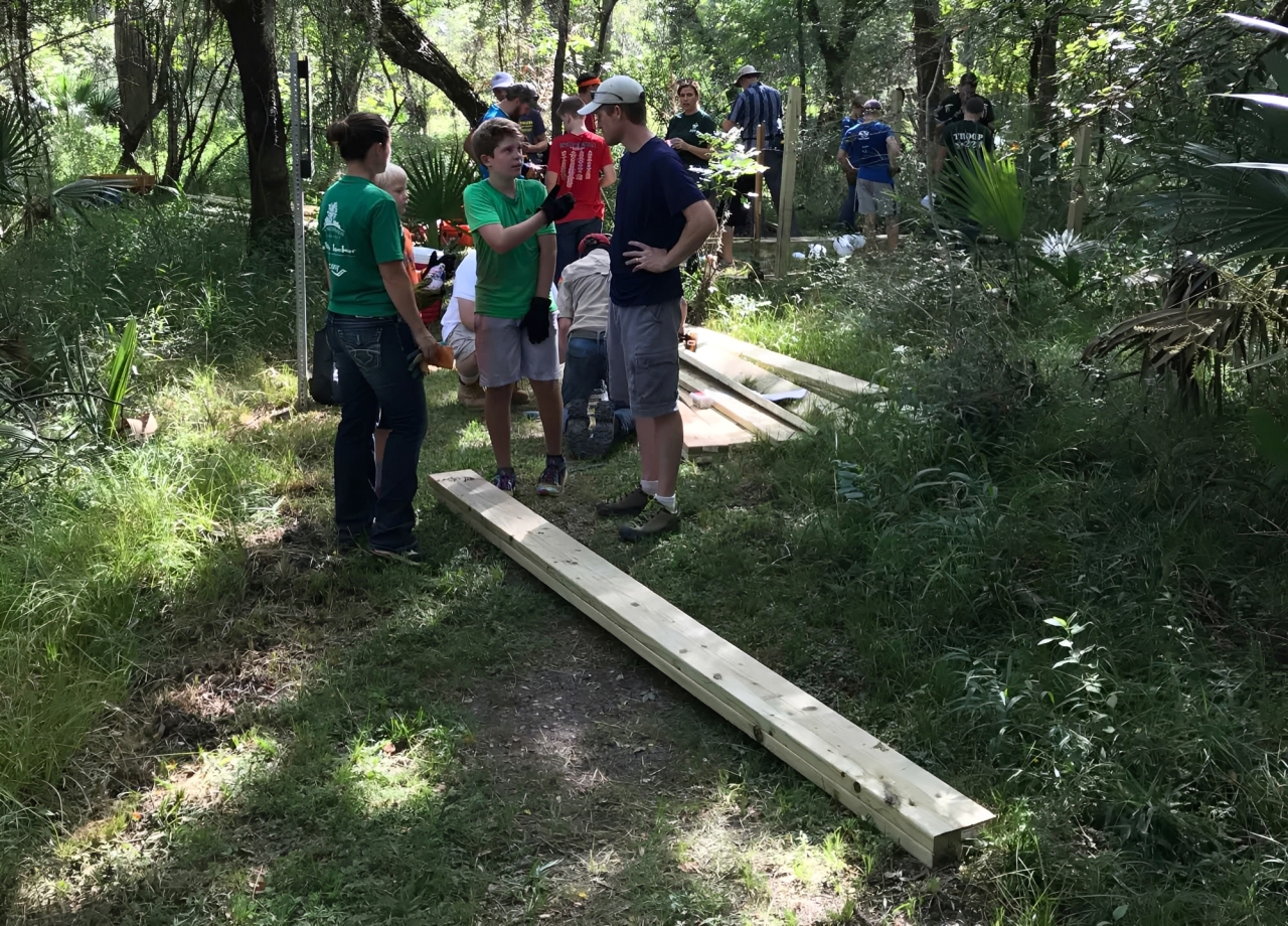 Group building wooden trail in woods