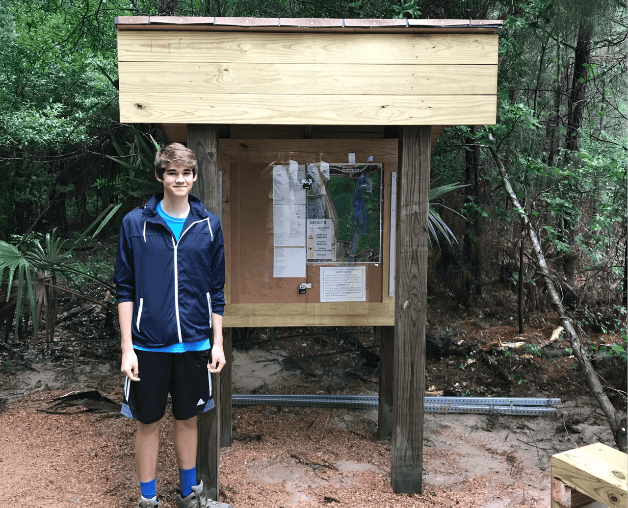 Teen in front of park information board