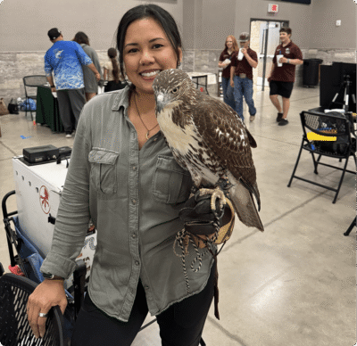 Smiling woman holding a hawk indoors